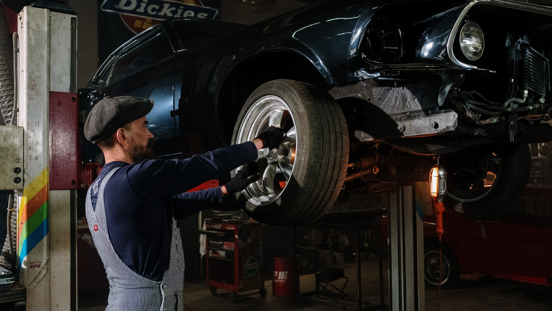 Person working on a car battery under an open hood